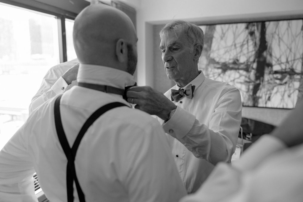 officiant putting on groomsmen bowties