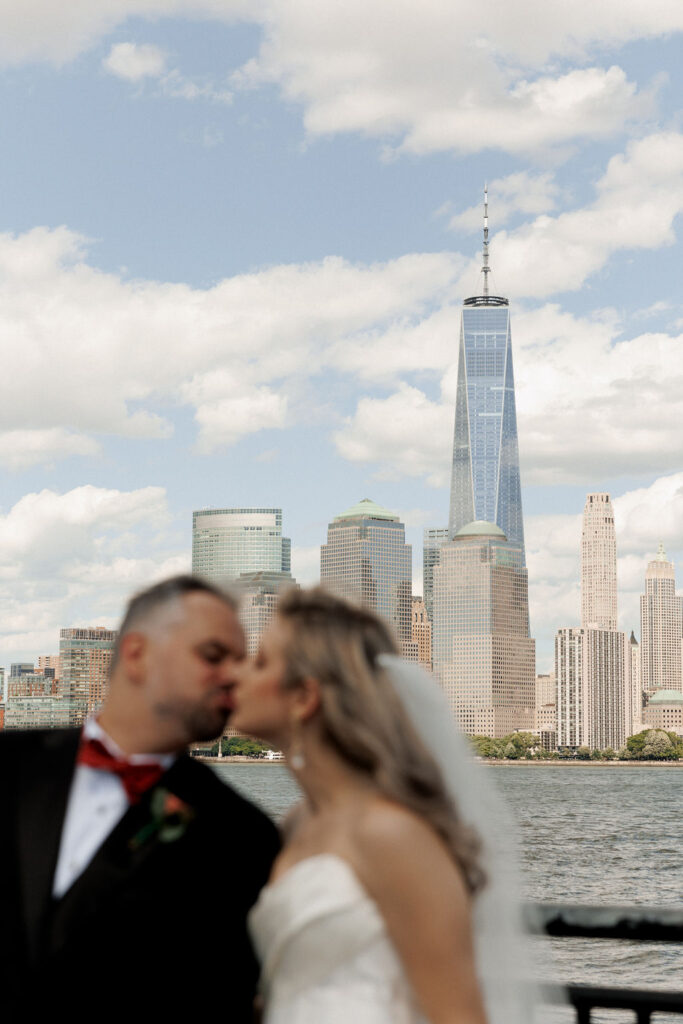 bride and groom kissing with New York skyline in the background